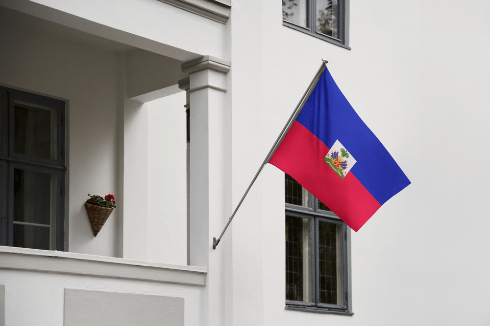 Haiti flag. Haitian flag hanging on a pole in front of the house. National flag waving on a home displaying on a pole on a front door of a building