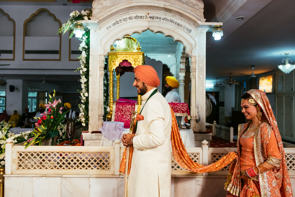 Groom leads the bride around the Holy book at the sikh wedding in gurudwara