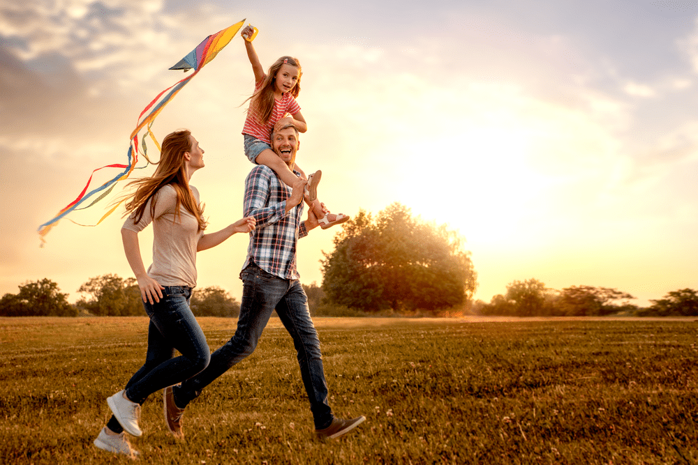 family-running-through-field-letting-kite